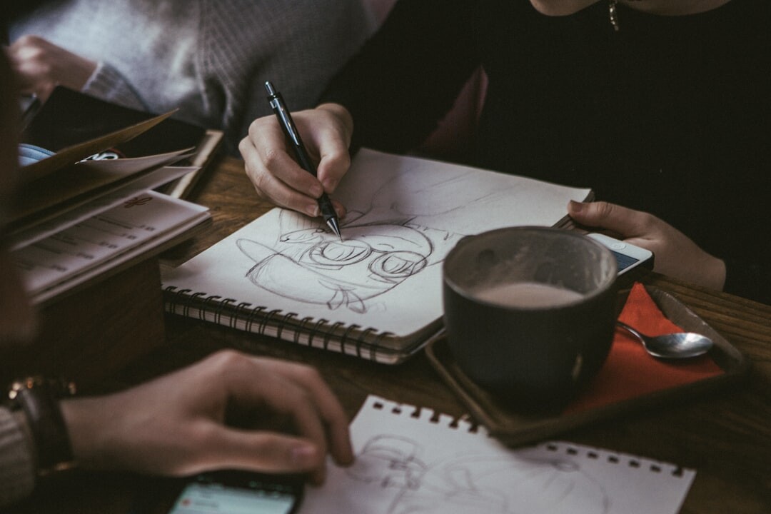 Person drawing with pencil on sketchbook